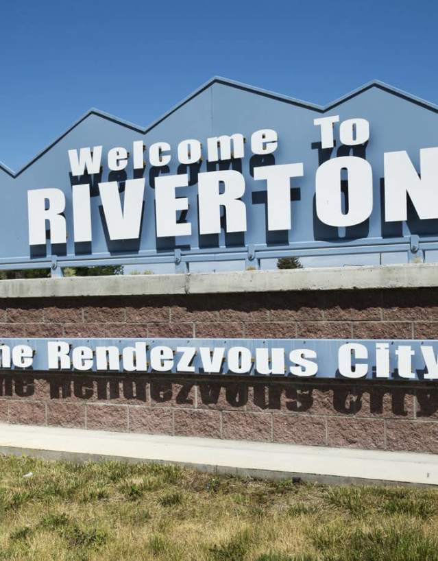 Welcome sign for Riverton, Wyoming, set next to a bronze statue in Fremont County.